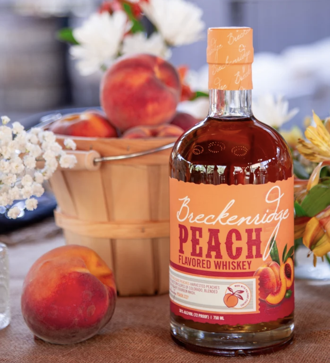 Breckenridge Peach Whiskey bottle beside a basket of fresh Palisade peaches, Colorado flavored whiskey 2026