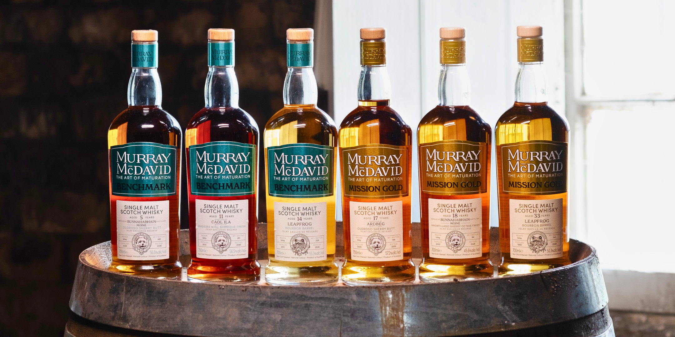Murray McDavid Islay Exclusive Release 2026, six Islay single malt whisky bottles on a cask, Benchmark and Mission Gold