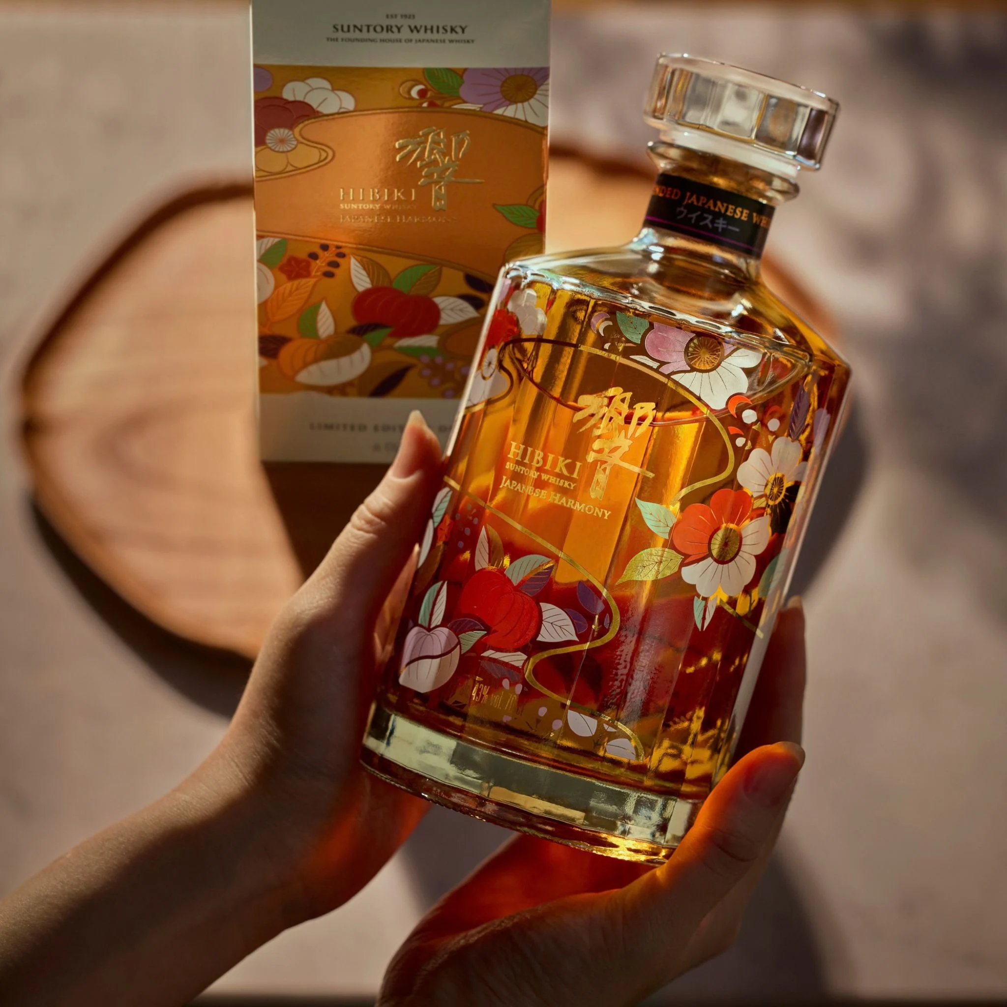 Hands holding the Hibiki Harmony Chiso 2026 70cl bottle in front of its matching limited edition gift carton